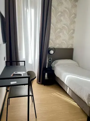 a bedroom with a bed and a desk and a window at Hotel Patria in Rome