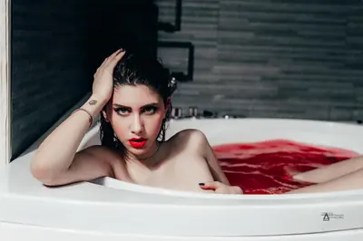 a woman laying in a bath tub with red lipstick at Gregorio VII Luxury Suites in Rome