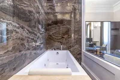 a bath tub in a bathroom with a stone wall at Internazionale Domus in Rome