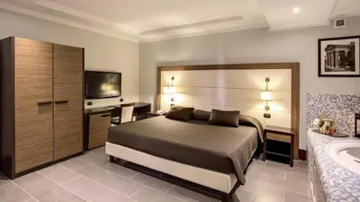 a bedroom with a bed and a desk and a television at The Strand Hotel in Rome