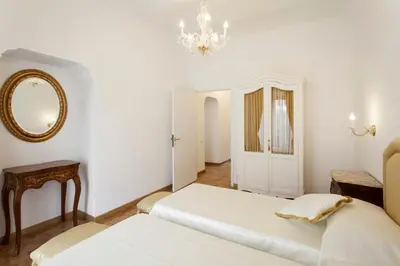 a white bedroom with two beds and a mirror at Suite Sarandrea in Rome