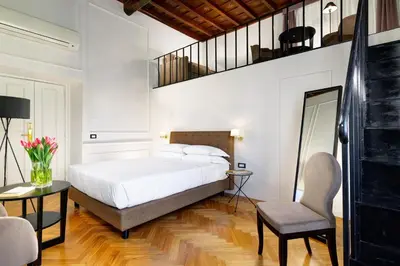 a bedroom with a bed and a table and a chair at Splendor Suite Rome - Suites & Apartments in Rome