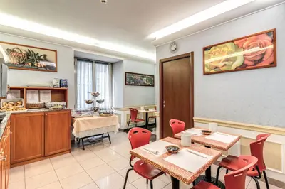 a dining room with tables and chairs and a kitchen at Hotel Milo in Rome