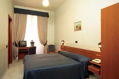 a hotel room with a blue bed and a desk at Hotel Dina in Rome