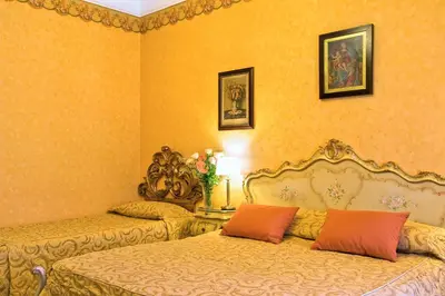 two beds in a room with yellow walls at Hotel Villa San Lorenzo Maria in Rome