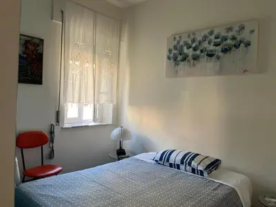 a bedroom with a bed and a window and a red chair at B&B Anni 50 in Rome