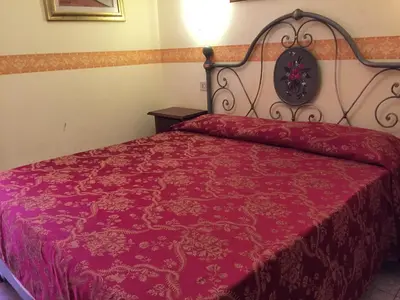 a bedroom with a red bed with a red comforter at Hotel Ventura in Rome