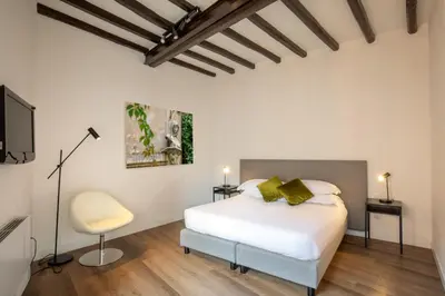 a white bedroom with a bed and a chair at Boutique Hotel Campo de' Fiori in Rome