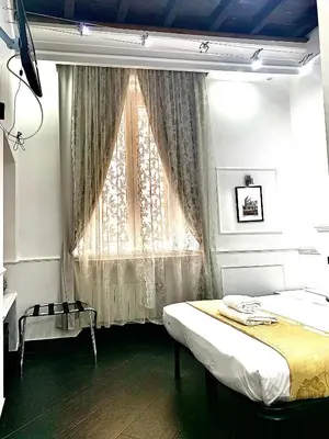 a bedroom with a bed and a window with curtains at L'antica Locanda Dell'Orso in Rome
