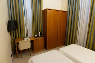 a hotel room with a bed and a desk and a cabinet at Crosti Hotel in Rome
