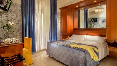 a bedroom with a bed with a yellow blanket on it at Hotel Assisi in Rome