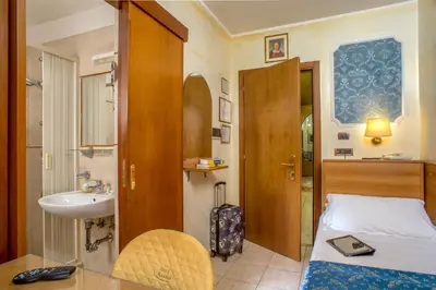 a small bathroom with a bed and a sink at Hotel Assisi in Rome