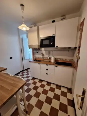 a kitchen with white cabinets and a checkered floor at Casa Vacanze Colosseo da Fernando no elevator in Rome