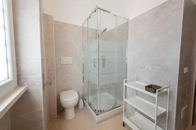 a bathroom with a toilet and a glass shower at Casa Rosa Beige e Blu in Rome