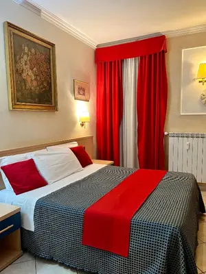 a bedroom with a large bed with red curtains at Città Eterna Guest House in Rome