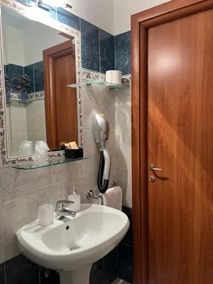 a bathroom with a sink and a wooden door at Città Eterna Guest House in Rome
