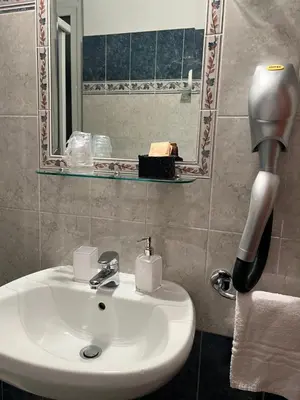 a bathroom with a sink and a blow dryer next to a mirror at Città Eterna Guest House in Rome