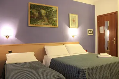 a bedroom with two beds and a painting on the wall at Città Eterna Guest House in Rome