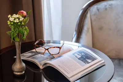 a table with a book and a vase of flowers and glasses at Relais Rione Ponte in Rome