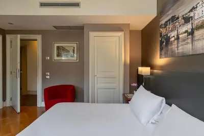 a bedroom with a white bed and a red chair at Hotel Principe Torlonia in Rome