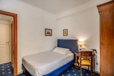 a small bedroom with a bed and a desk at Hotel Napoleon in Rome