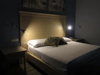 a bedroom with a bed with a headboard and two tables at Casa Eli Roma B&B in Rome