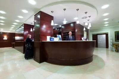 two people standing at a counter in a lobby at Hotel Delle Nazioni in Rome