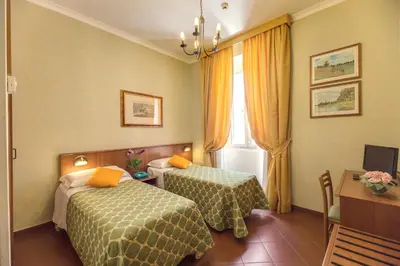 a hotel room with two beds and a window at Hotel Corona in Rome