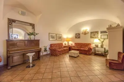 a living room with a piano and couches and a mirror at Hotel Corona in Rome