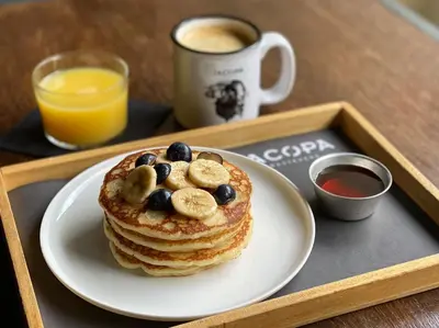 a plate of pancakes with bananas and blueberries on a tray at Hotel San Francesco in Rome