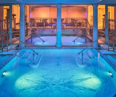 a pool of water with columns in a building at Rome Cavalieri, A Waldorf Astoria Hotel in Rome
