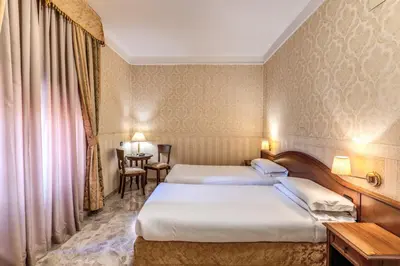 a hotel room with two beds and a table at Hotel Orazia in Rome