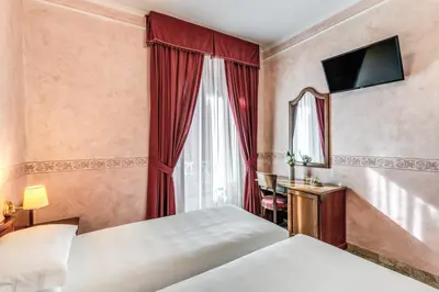 a hotel room with two beds and a mirror at Hotel Orazia in Rome