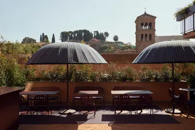 two tables and chairs under umbrellas on a patio at Palazzo Velabro, a Member of Design Hotels in Rome