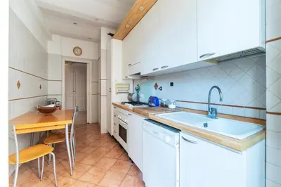 a kitchen with white appliances and a wooden table at GuestHost - MM Cipro Elegant Apartment in Rome