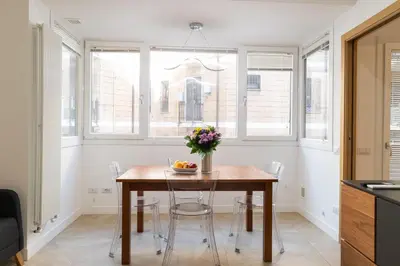 a dining room with a table and chairs and windows at Casa Camilla in Rome