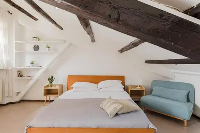 a bedroom with a bed and a blue chair at La mansarda del Papa - ZENO 05 in Rome