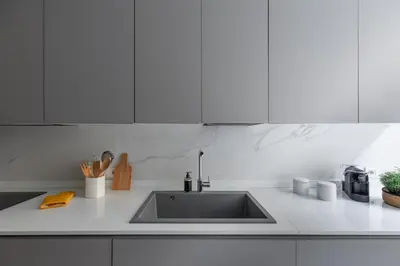 a kitchen counter with a sink and white cabinets at iFlat Vatican Elegant Apartment in Rome