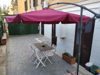 a purple umbrella on a patio with a table and chairs at OFFICINALE Rome Apartment, Pineta Sacchetti in Rome