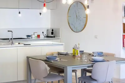 a kitchen with a table with chairs and a clock on the wall at Ottavia al Foro - Luxury Property in Rome