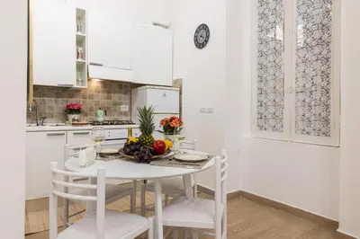 a white kitchen with a white table and chairs at Le Stanze di Rinaldo in Rome