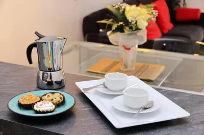 a table with two cups and a plate with cupcakes and a coffee maker at 4BNB - Cozy Albornoz Flat in Rome
