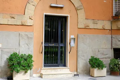 an orange building with a black door and two plants at Remuria Domus in Rome