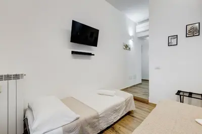 a white room with a bed and a tv on a wall at VATICANDREAM GUEST HOUSE in Rome