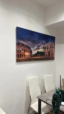 a painting hanging on a wall with a table and chairs at Moderno appartamento Cornelia-San Pietro con Giardino in Rome