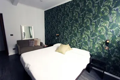 a bedroom with a white bed with a green wallpaper at Avignonesi Flat in Rome