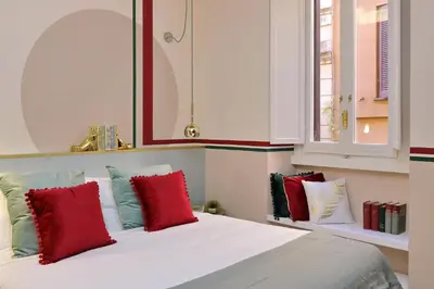 a bedroom with a bed with red and green pillows at YCH-Bright Suite Navona in Rome
