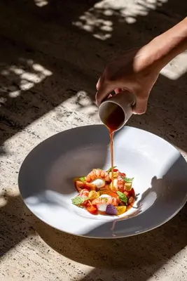 a person is pouring sauce on a plate of food at The Rome EDITION in Rome