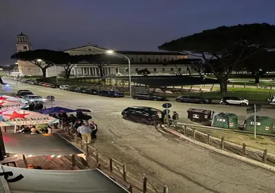 a group of people standing in a parking lot at night at StarHome San Paolo in Rome