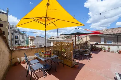 a patio with a table and a yellow umbrella at Monti Coliseum 2nd floor 3 bedroom in Rome
